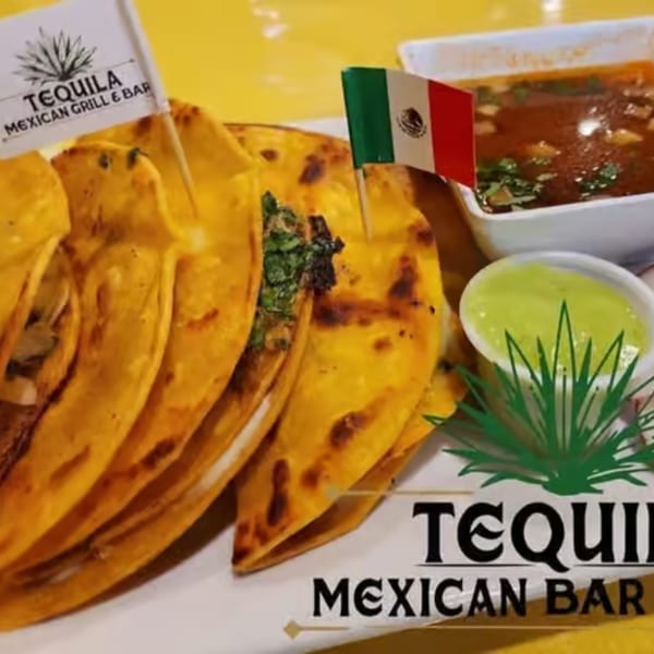 Tequila Mexican Grill & Bar's birria tacos with consommé and green sauce, adorned with Mexican flags.