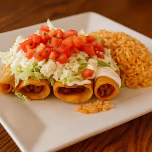Three golden taquitos topped with lettuce, diced tomatoes, sour cream, and a side of orange rice.
