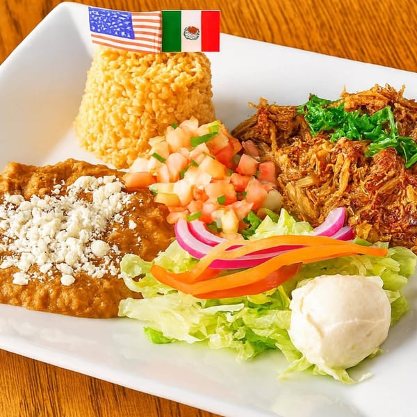 A Mexican dish with rice, refried beans, shredded meat, pico de gallo, salad, and sour cream.