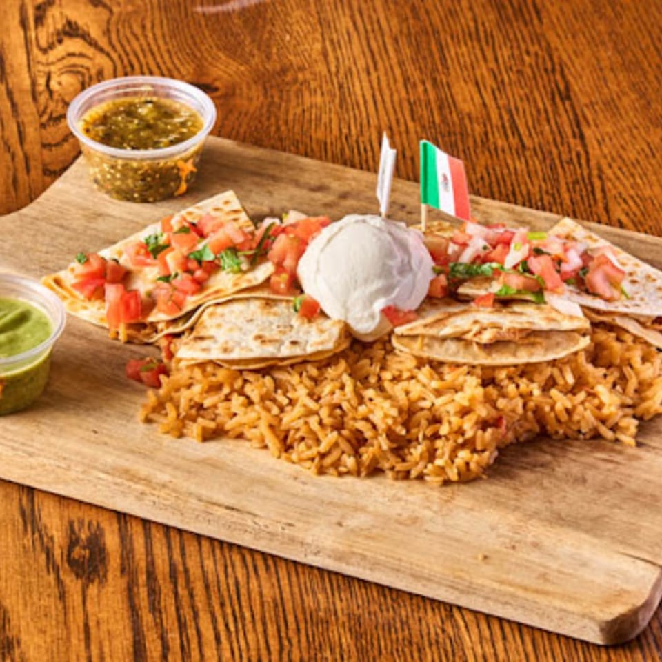 Mexican-style tacos topped with pico de gallo, rice, sauces, and sour cream arranged on a wooden serving board.