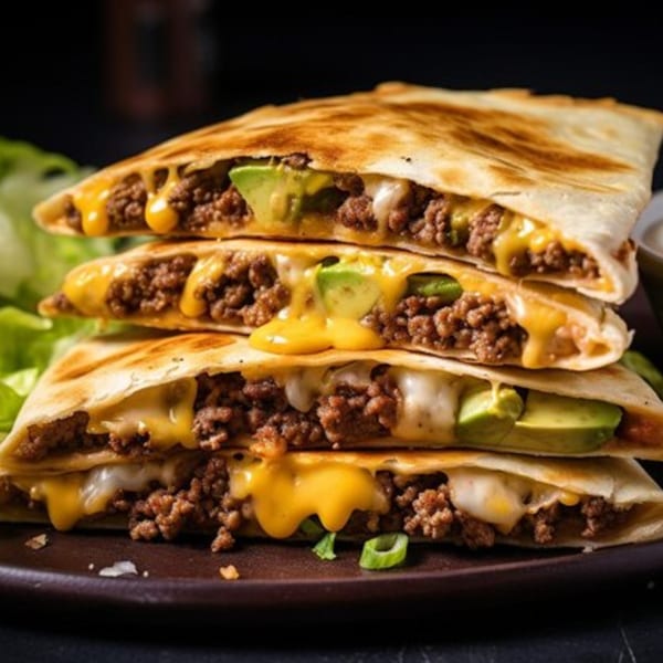 Stacked beef and cheese quesadillas with avocado slices, melted cheese, and green onions.